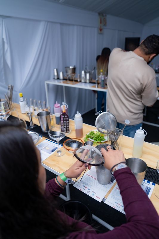 A guest straining a cocktail at a Mixology Theatre station