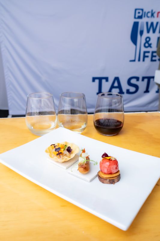Canapés plated beside a flight of three festival wine glasses
