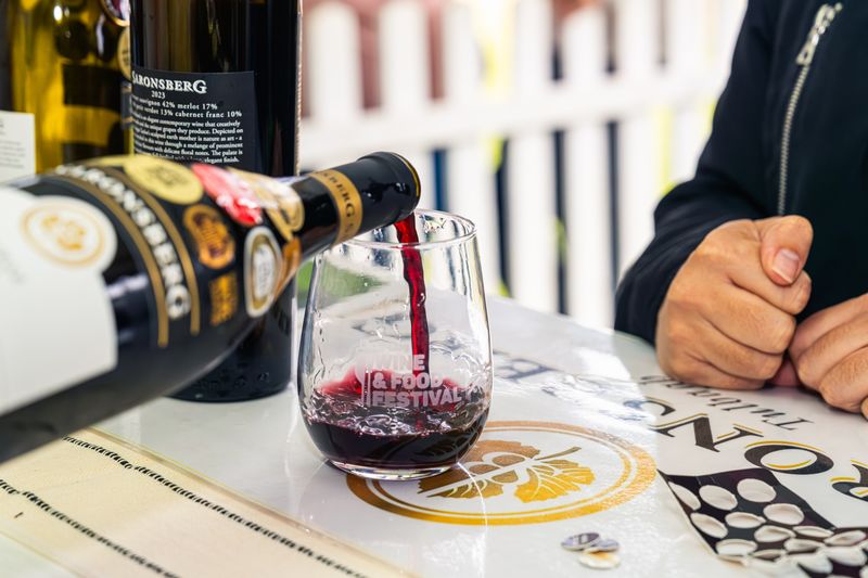Red wine poured into a branded festival glass at a producer stand