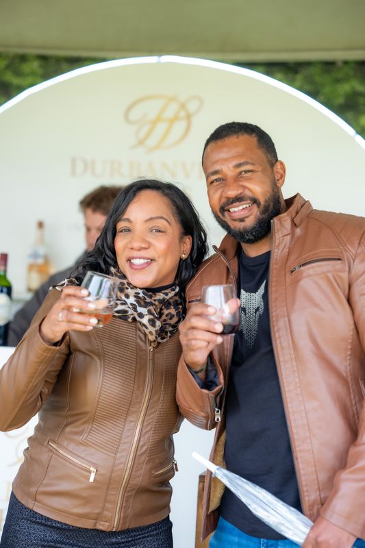 Two festival guests toasting with wine at a producer stand